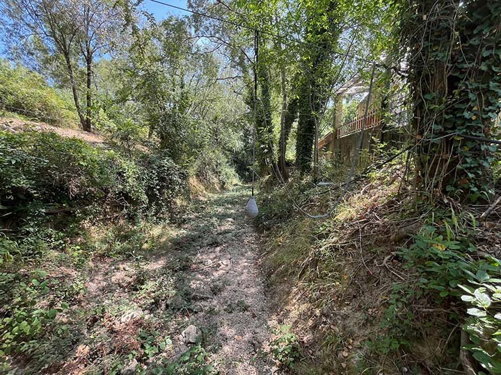 Le ravin d'Embarre à sec, avec le capteur-poire d'alerte et la clôture de l'école maternelle La Source en arrière-plan